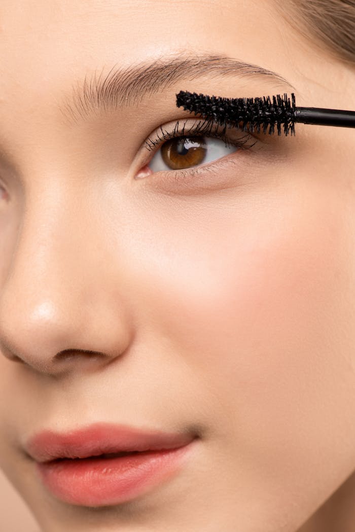 Detailed close-up of a woman applying mascara to emphasize lashes and eye beauty.